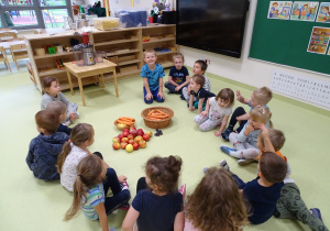 01 Dzieci siedzą w kole wokół koszy z warzywami i owocami